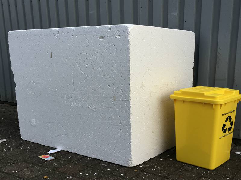 Gros bloc de polystyrène d'emballage près d'une poubelle pour les consignes de tri.